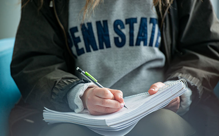 Penn State student taking notes in a notebook